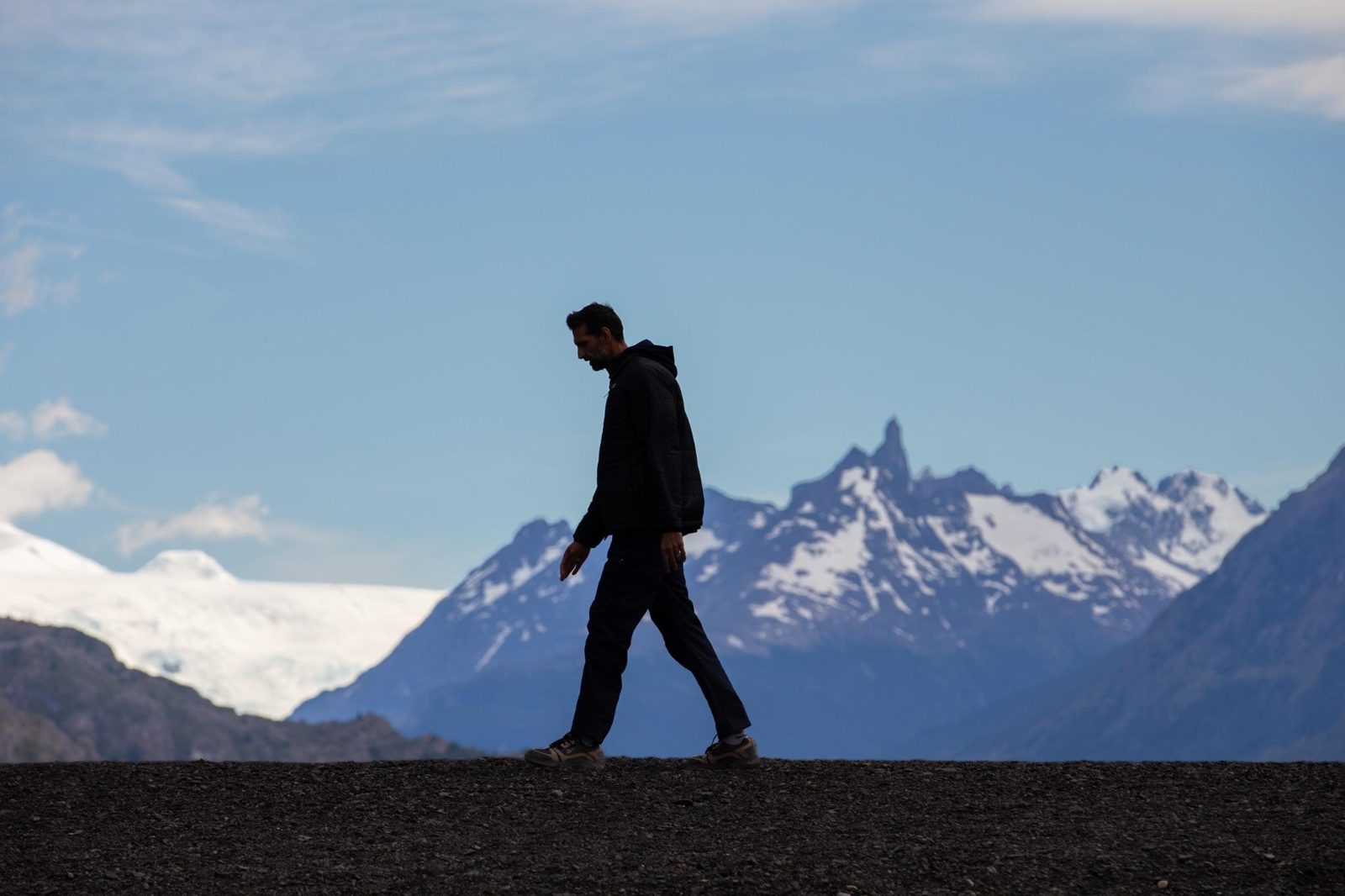 A lone figure walks along a ridge in front of snow-capped mountains in Patagonia
