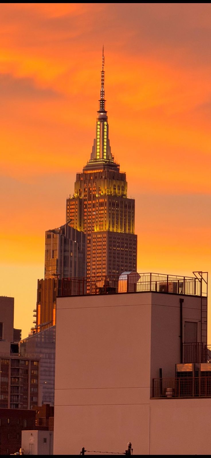 The Empire State Building against an orange sunset sky